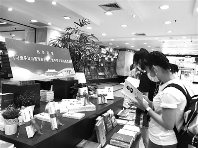 圖為讀者近日在上海書城設(shè)置的《習(xí)近平談治國理政》第三卷專架展臺前閱讀。  外文出版社供圖