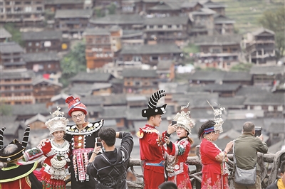 近年來，貴州省雷山縣不斷推動高鐵資源和旅游景區(qū)深度融合，方便各地游客前來體驗(yàn)苗族風(fēng)情，觀賞苗寨美景，為古老苗寨的鄉(xiāng)村振興注入活力。圖為今年國慶假期，游客穿著民族服裝在該縣西江千戶苗寨觀景臺拍照留念。新華社發(fā)（林世康 攝）